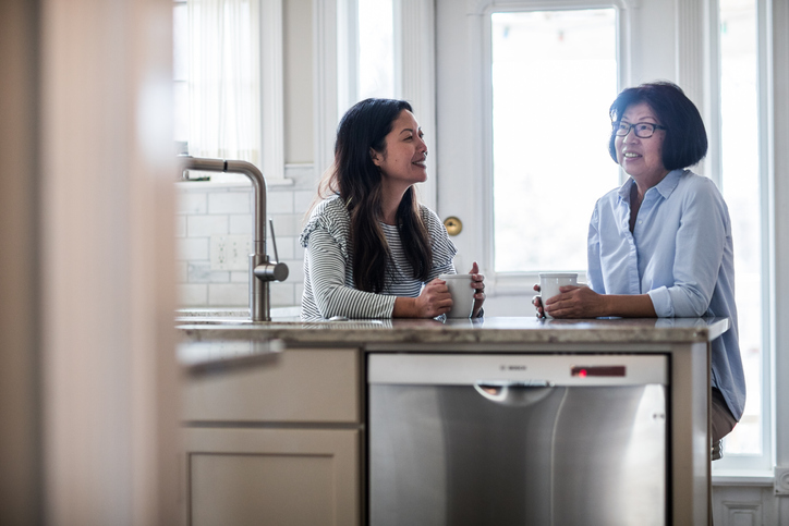 mother and adult daughter having coffee in kitchen